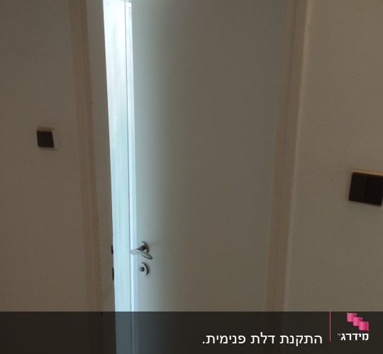 דלת לבנה פתוחה למחצה עם ידית מתכת